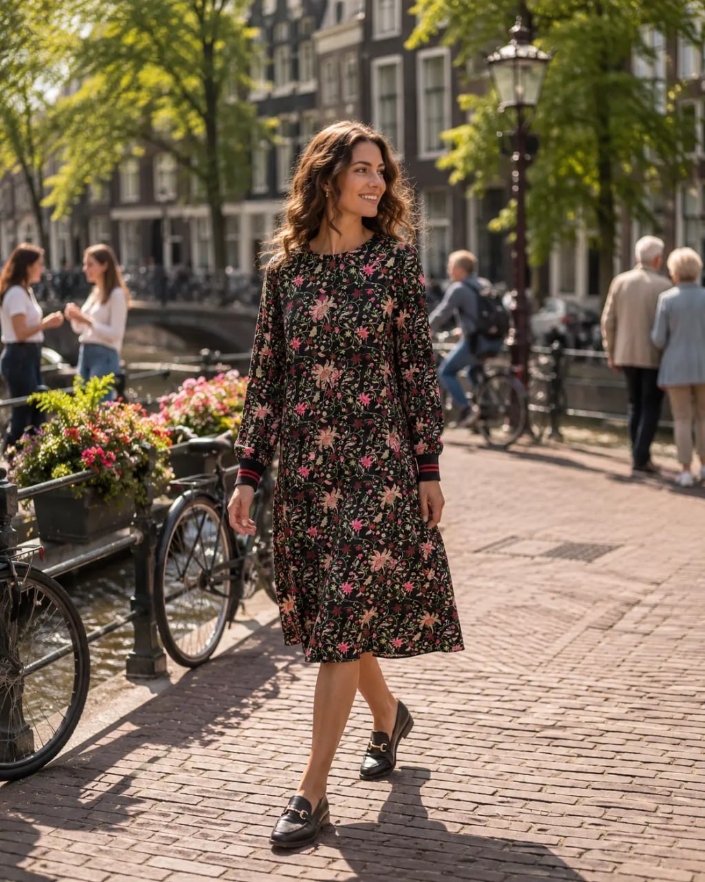 Woman in a floral dress walking on a street with canal and buildings in the background