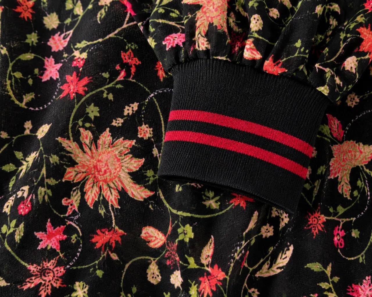 Close-up of a black sock with red stripes on a floral-patterned fabric background