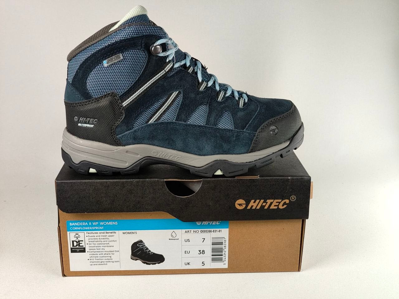 A blue and gray HITEC hiking boot displayed on top of its brown cardboard shoebox against a plain white background.