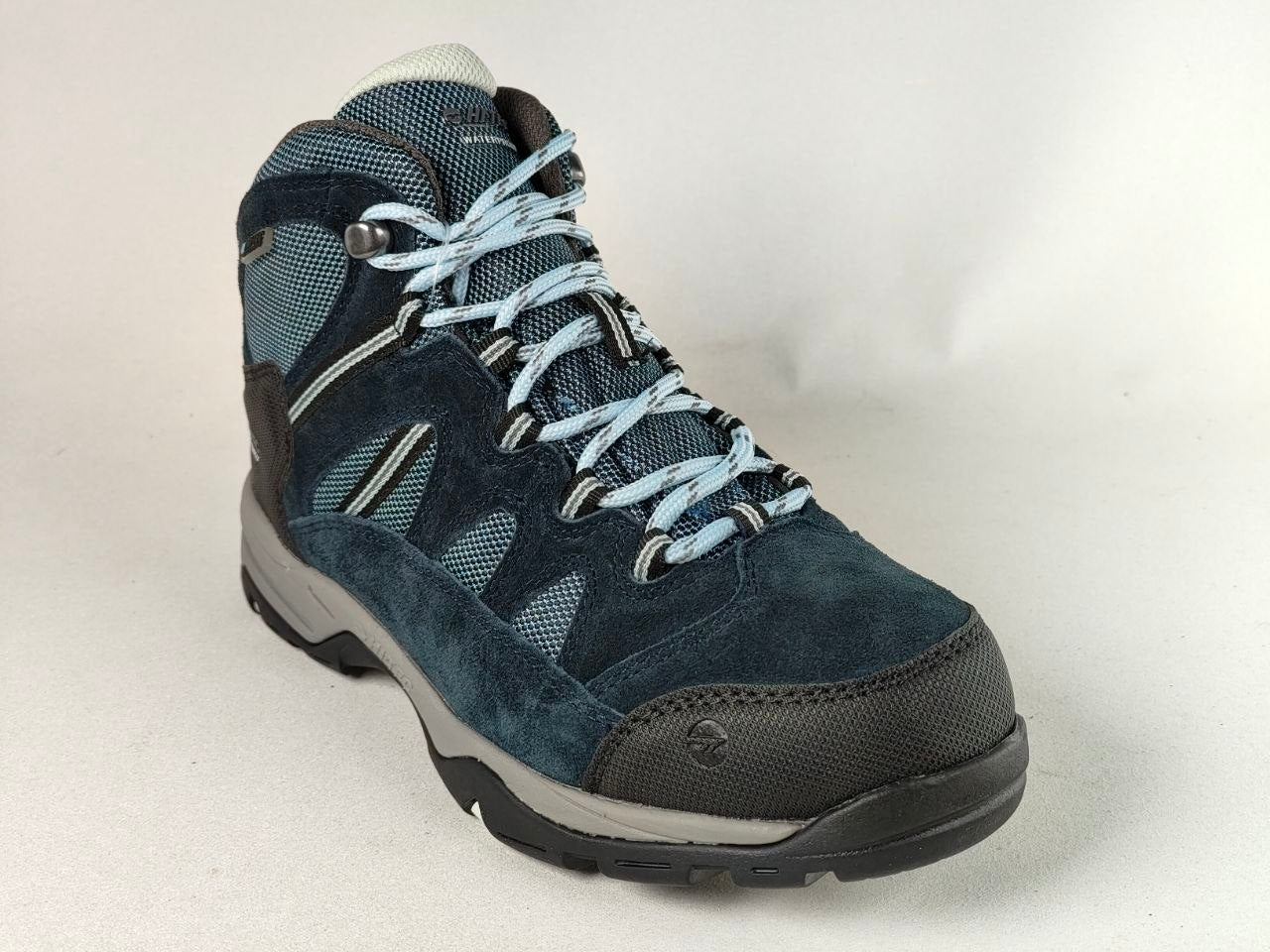 A dark blue suede and mesh hiking boot with light blue laces, a black toe cap, and a gray midsole, photographed on a light gray background.