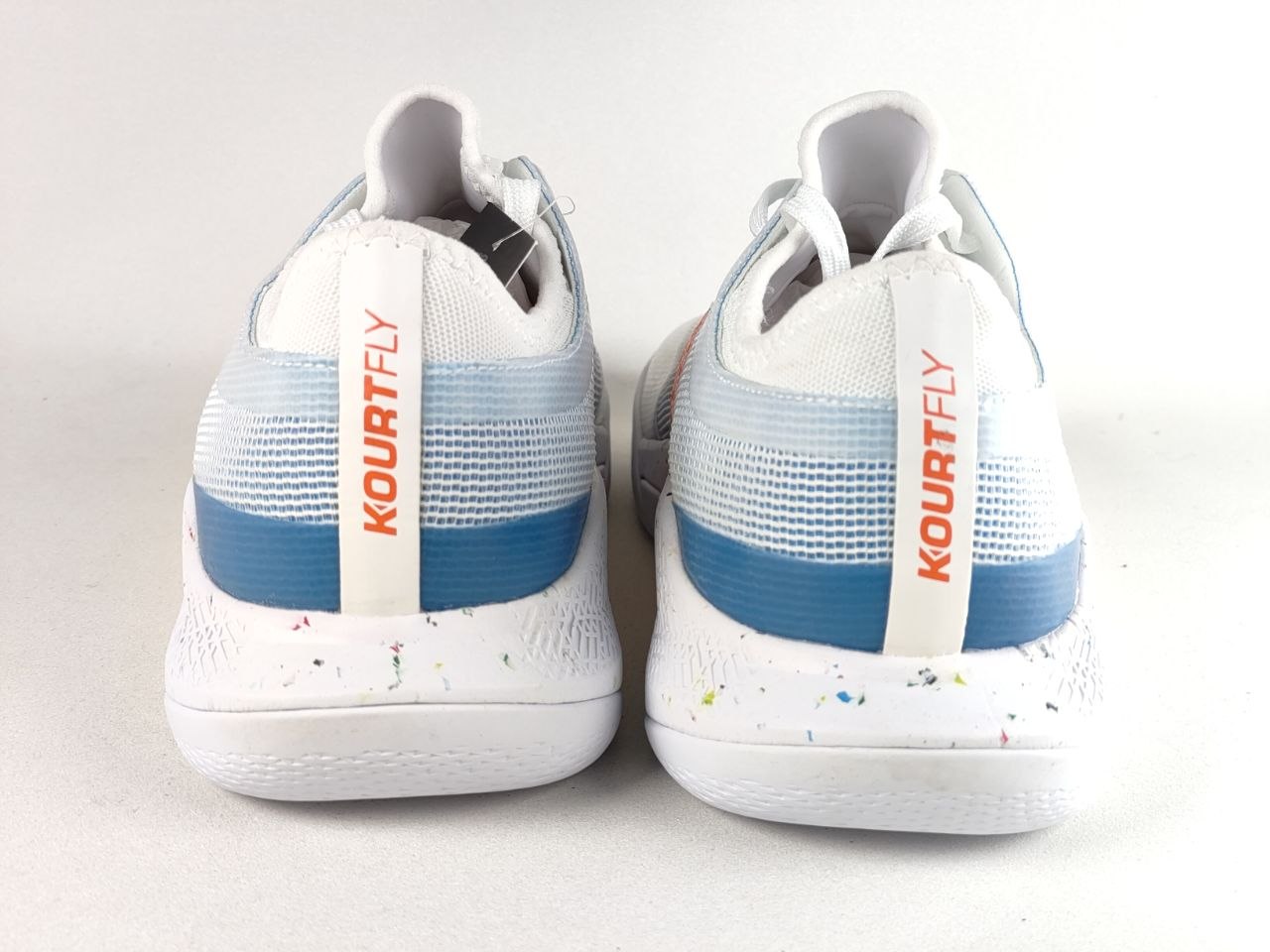 A pair of Kourt Fly athletic shoes shown from the back, featuring a white mesh upper with light blue gradient stripes, a blue horizontal band, and a white heel insert with orange 'KOURTFLY' branding.