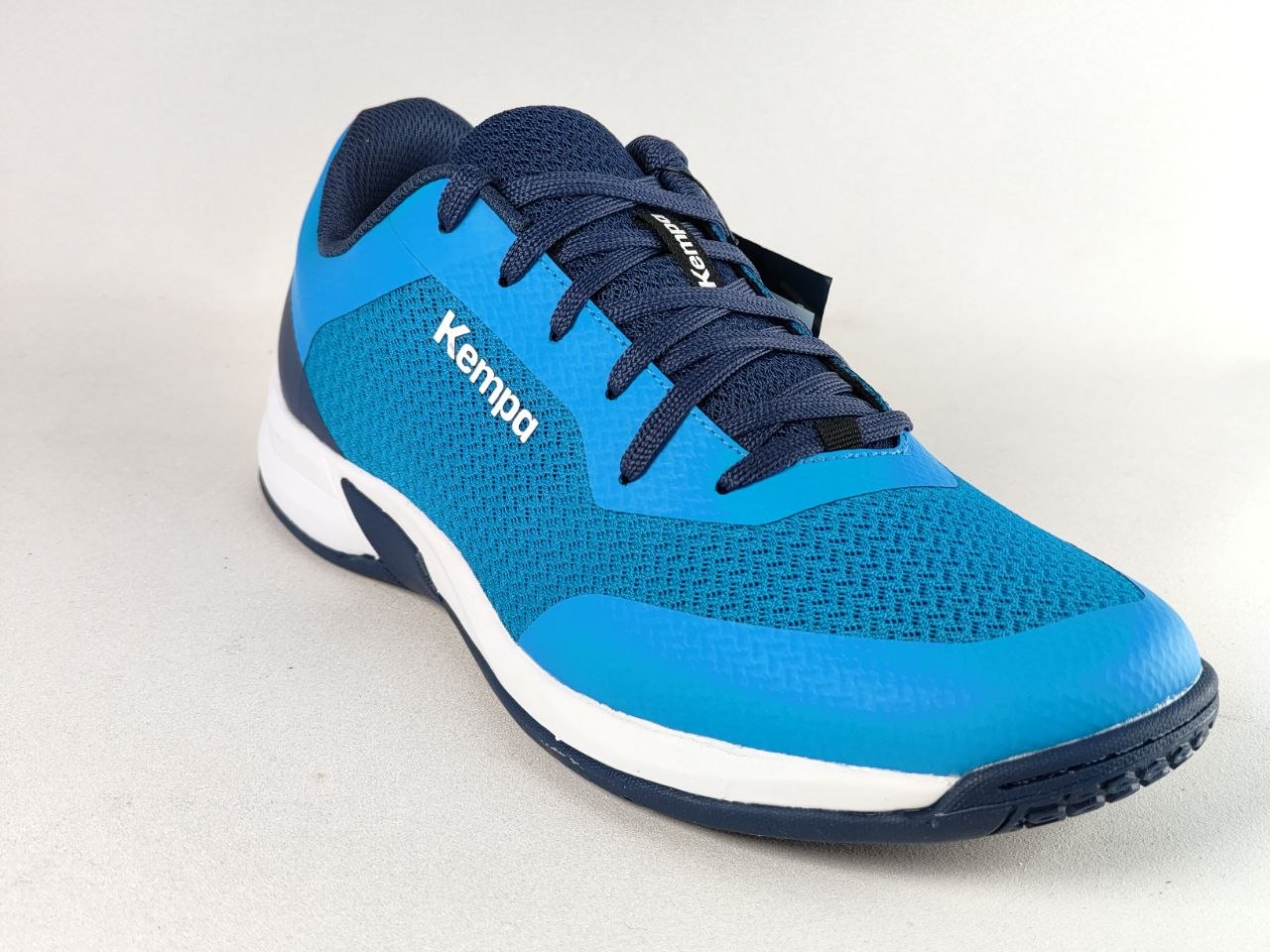 A Kempa athletic shoe in bright blue and navy blue, featuring a textured knit upper, white midsole, and navy outsole, shown on a light gray background.