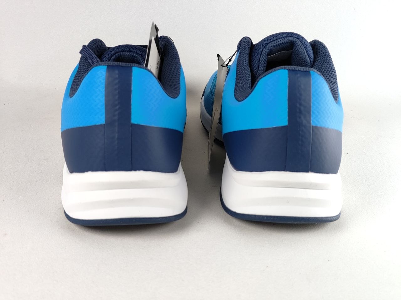 A pair of athletic sneakers shown from the back, featuring a color-blocked design with bright blue and navy blue panels on a white sole.