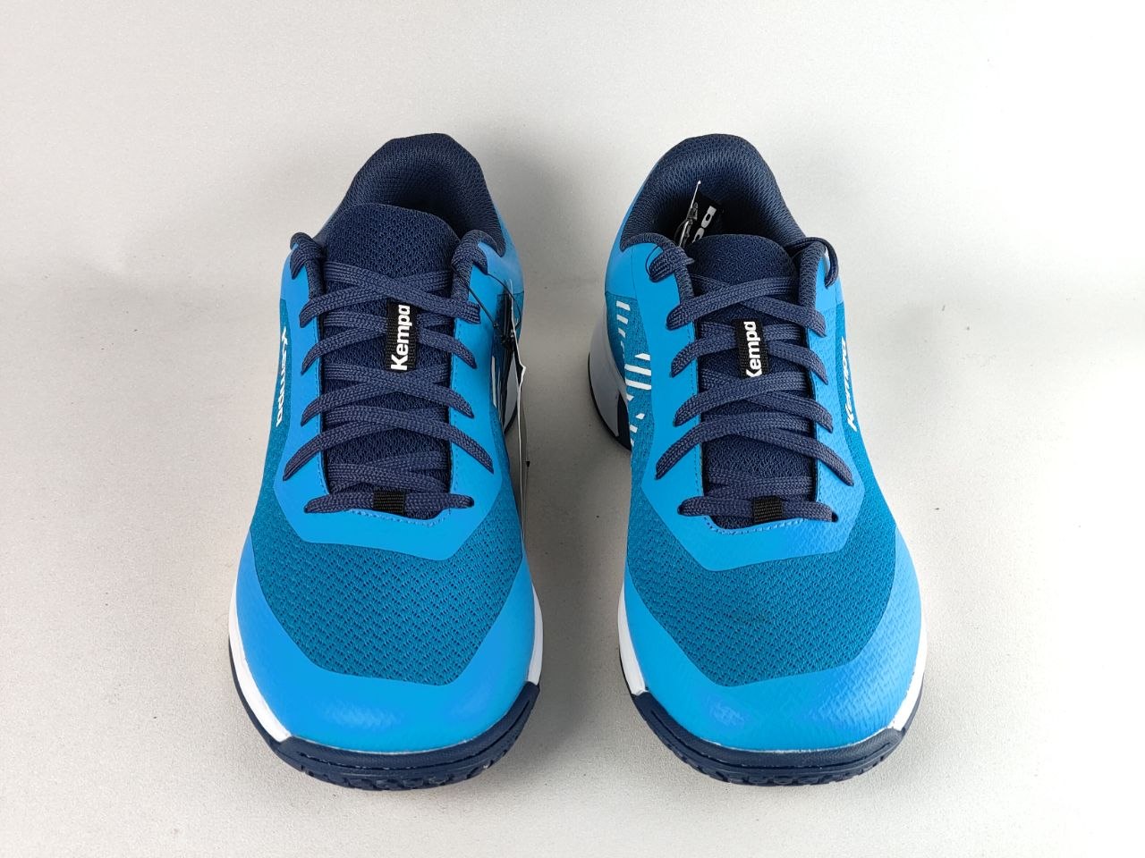 A pair of Kompa athletic sneakers in bright blue and navy blue, shown from a top-down view on a light gray background.