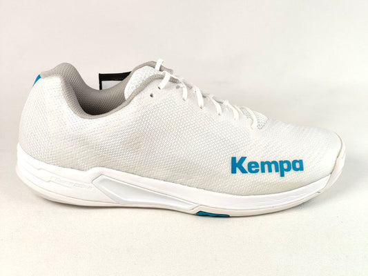 A white Kempa athletic shoe with a textured mesh upper, white laces, and a white sole with blue branding and a small blue accent near the heel, shown against a light off-white background.