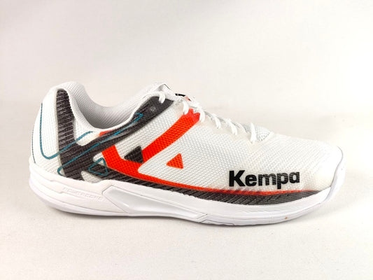 A white Kempa athletic shoe with a white mesh upper, featuring a prominent orange-red side stripe, a black textured heel accent, and the black 'Kempa' brand name on the side, set against a plain light background.