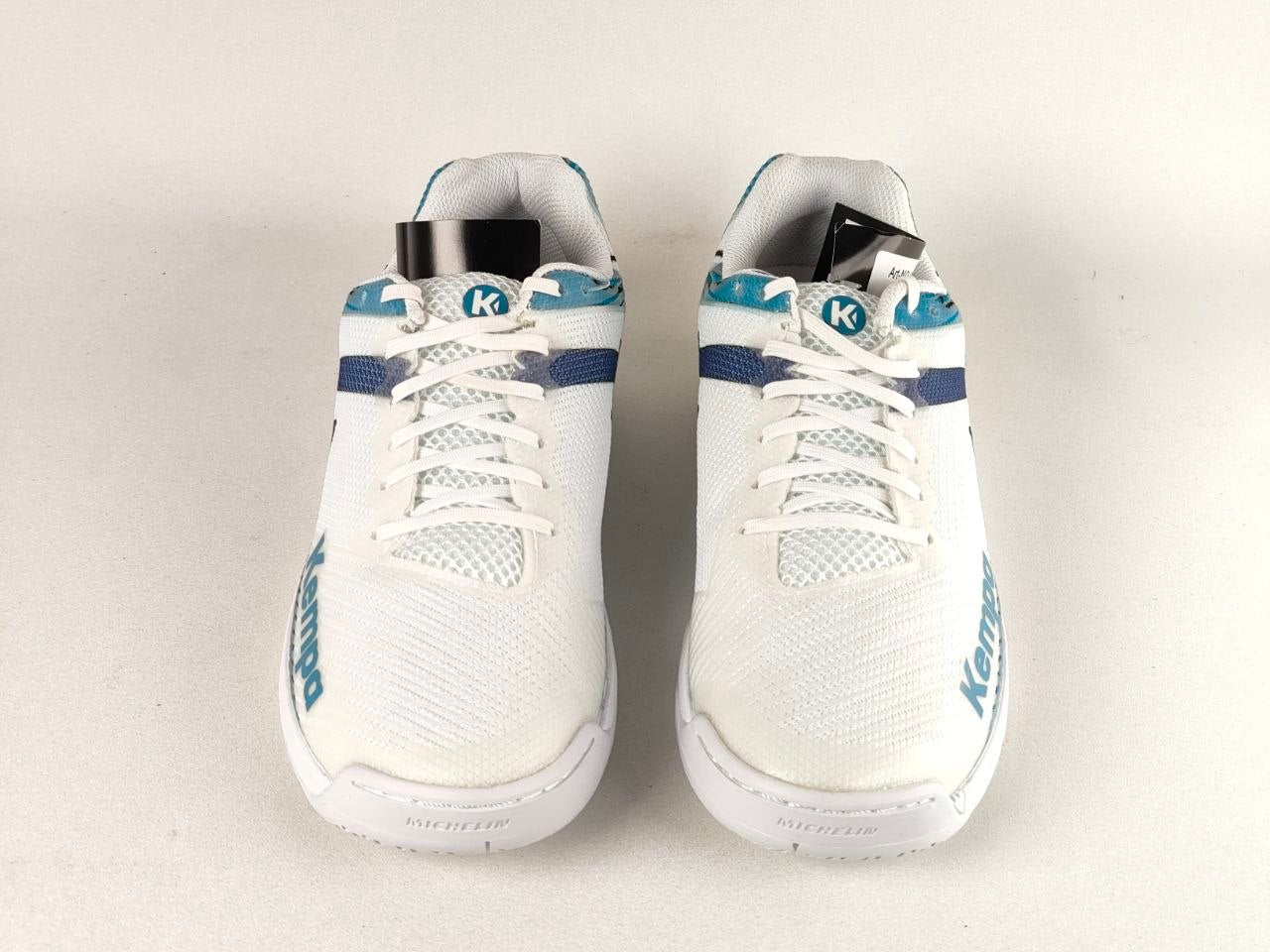 A pair of white Kari Traa athletic shoes with blue accents and white laces, shown from a front-facing perspective on a light gray background.