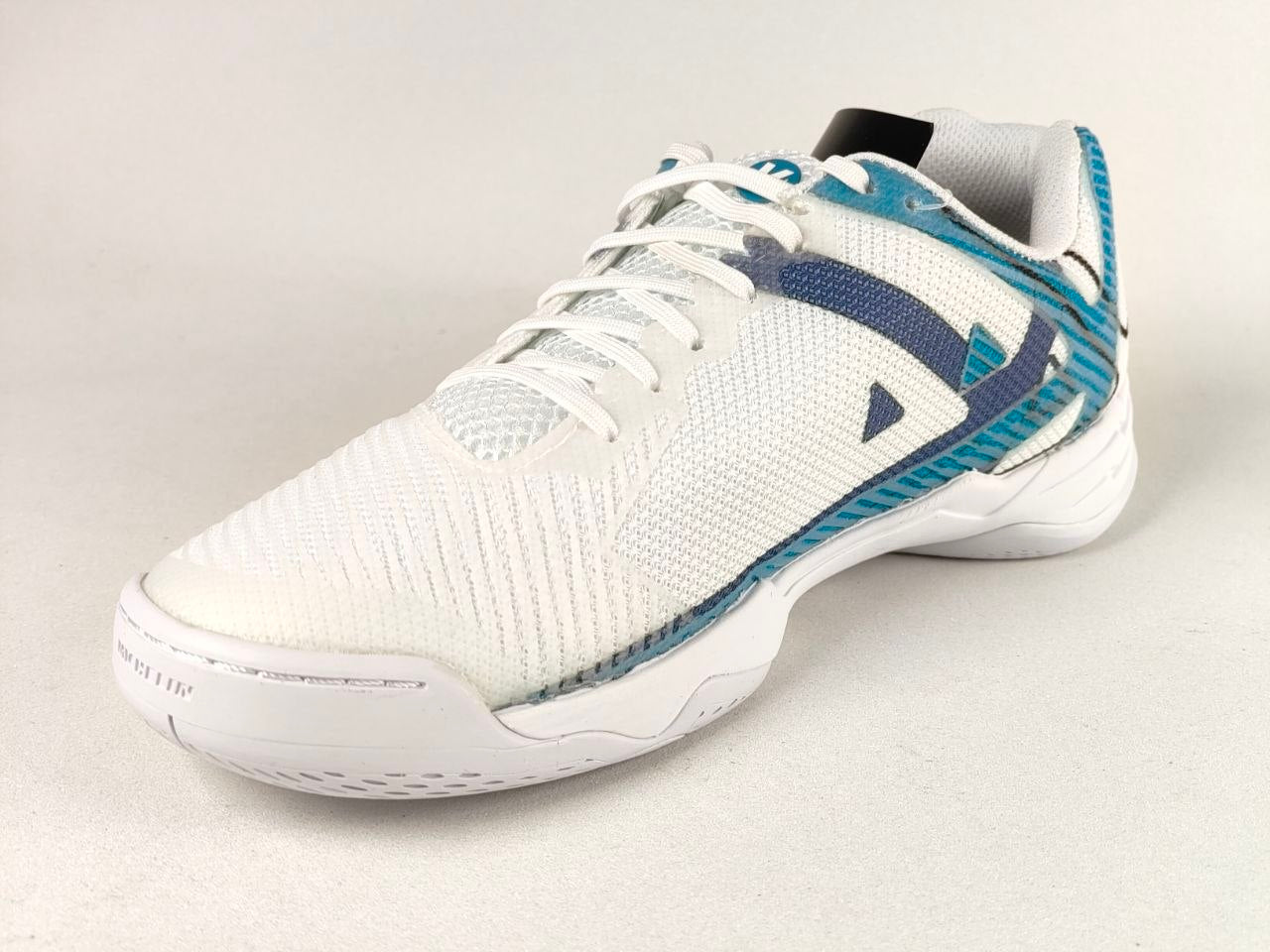 A white athletic shoe with blue and teal accents, featuring a textured knit upper, white laces, and a white sole, photographed on a light gray background.