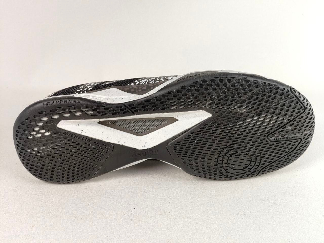 The outsole of a black and white athletic shoe, showing a textured black tread pattern with a white accent panel and the brand name 'BONJOUR' visible on the heel area.