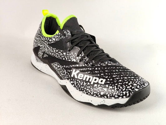 A black and white speckled Kempa athletic shoe with a bright neon yellow-green collar and tongue pull tab, shown on a light gray background.