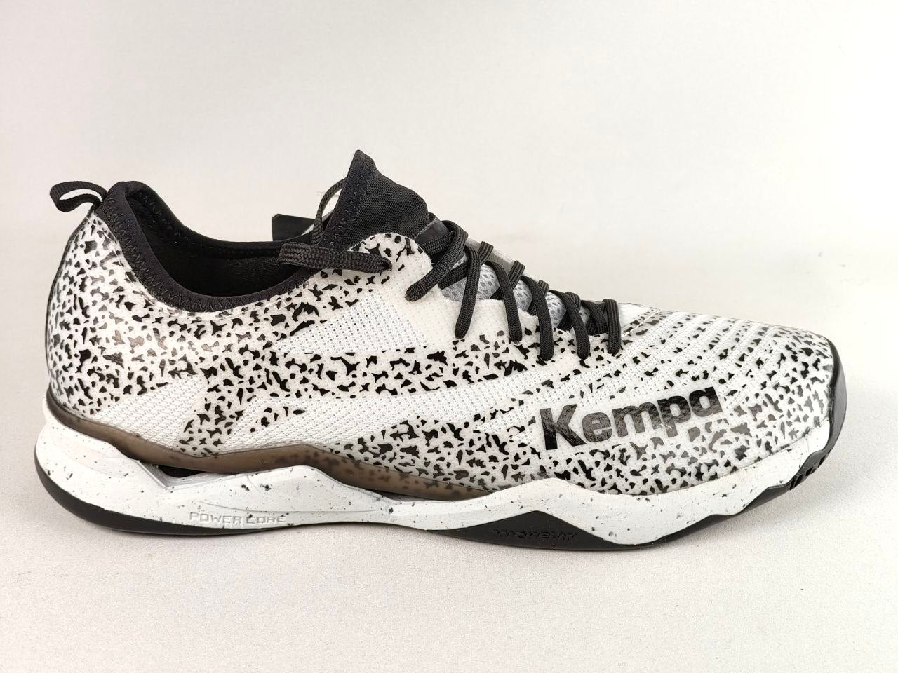 A Kempa athletic shoe featuring a white and black speckled pattern, black laces, and a black and white sole, shown against a plain light background.