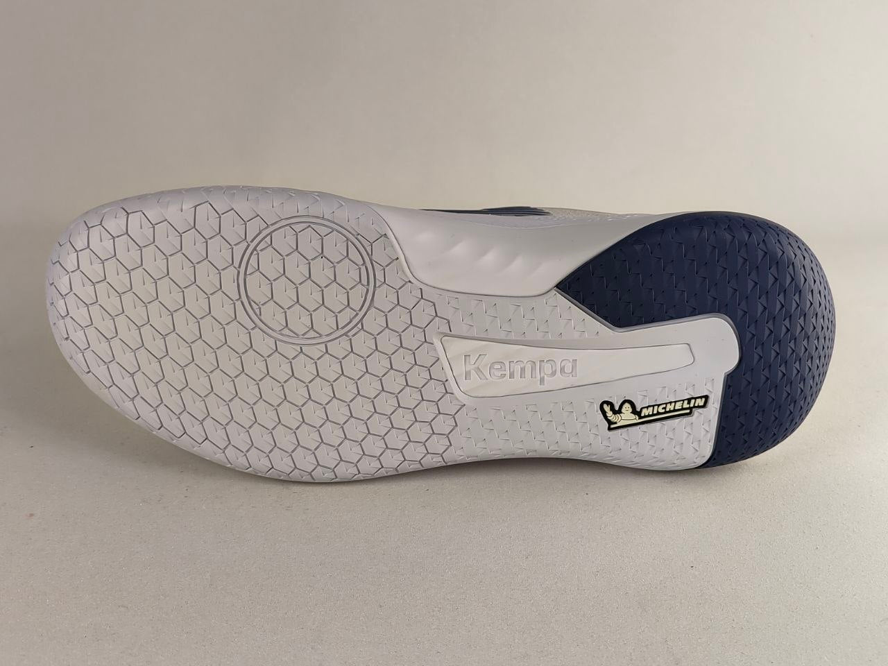 The outsole of a Kempa indoor soccer shoe, showing a white honeycomb-patterned tread with a dark navy blue heel and a visible Michelin logo.