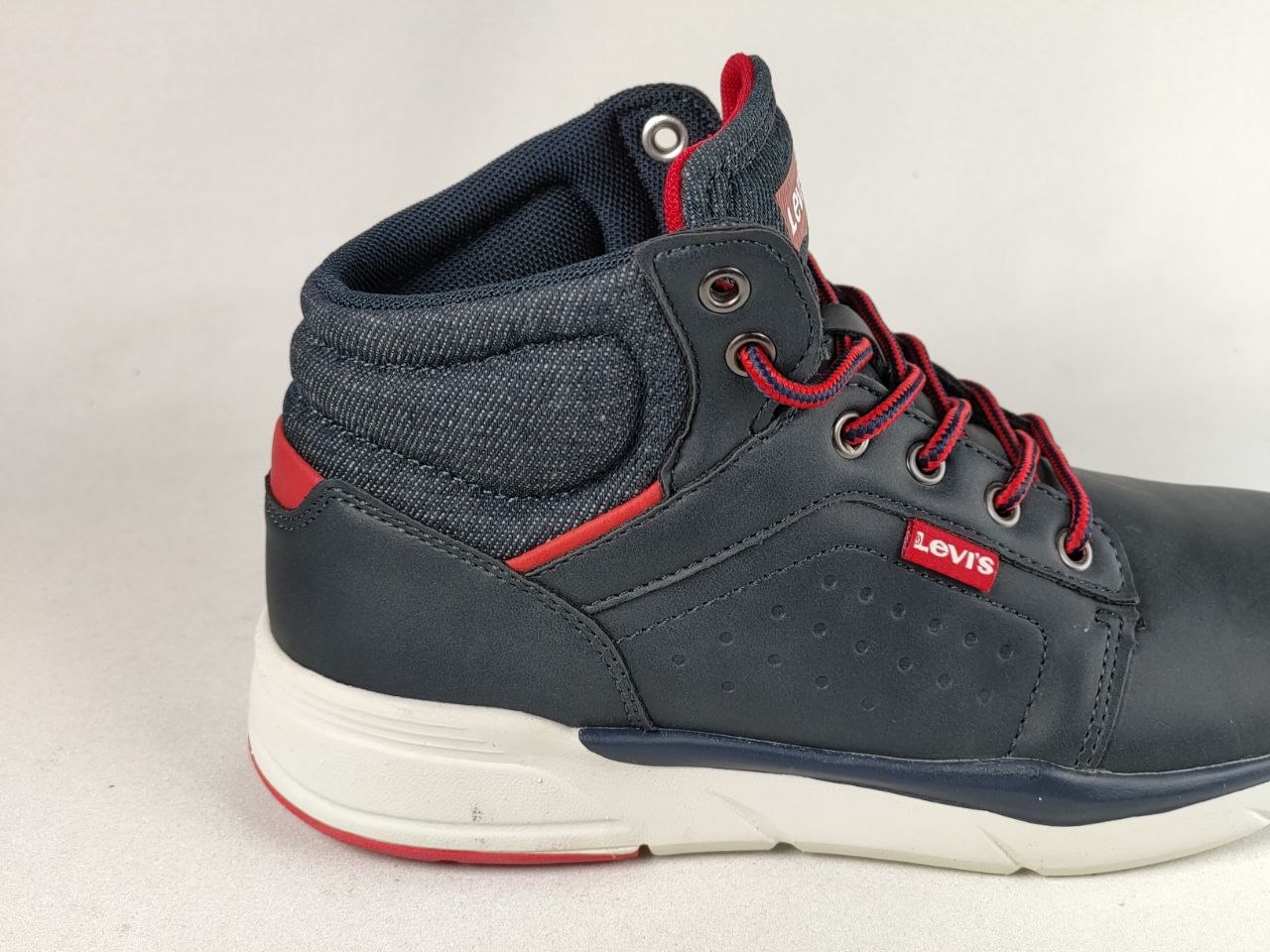 A navy blue Levi's high-top sneaker with red laces, red accents, and a white sole, shown from a side profile view against a light gray background.