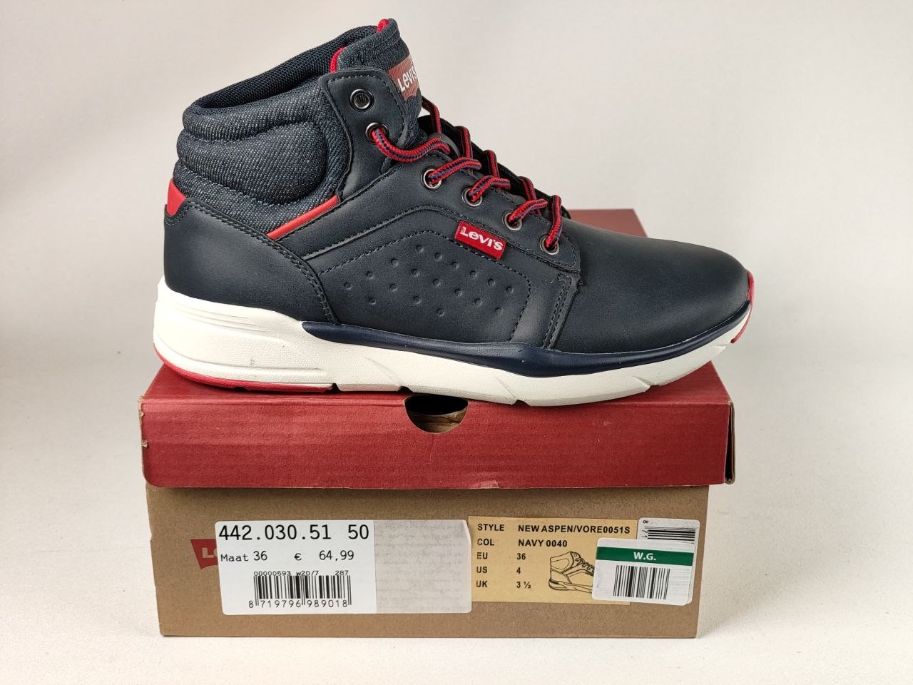 A navy blue Levi's mid-top sneaker with red laces and red accents, resting on its brown cardboard shoebox against a light gray background.