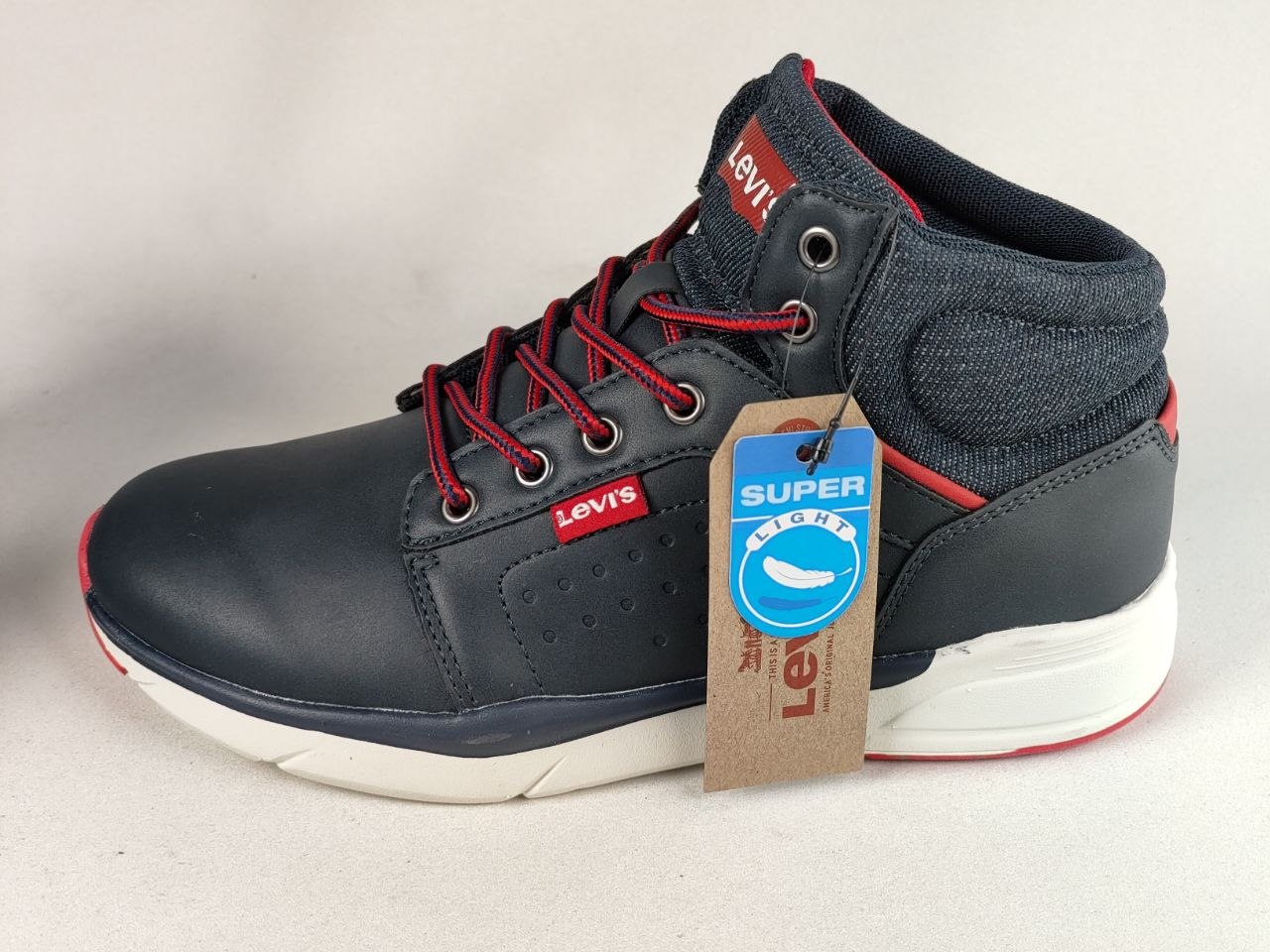 A navy blue and gray Levi's high-top sneaker with red laces, a white midsole, and a brown paper hangtag attached, photographed on a light gray background.