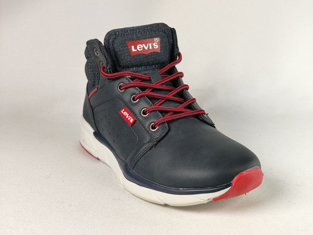 A single Levi's high-top sneaker in navy blue with red laces, a red toe cap, and a white midsole, photographed on a light gray background.