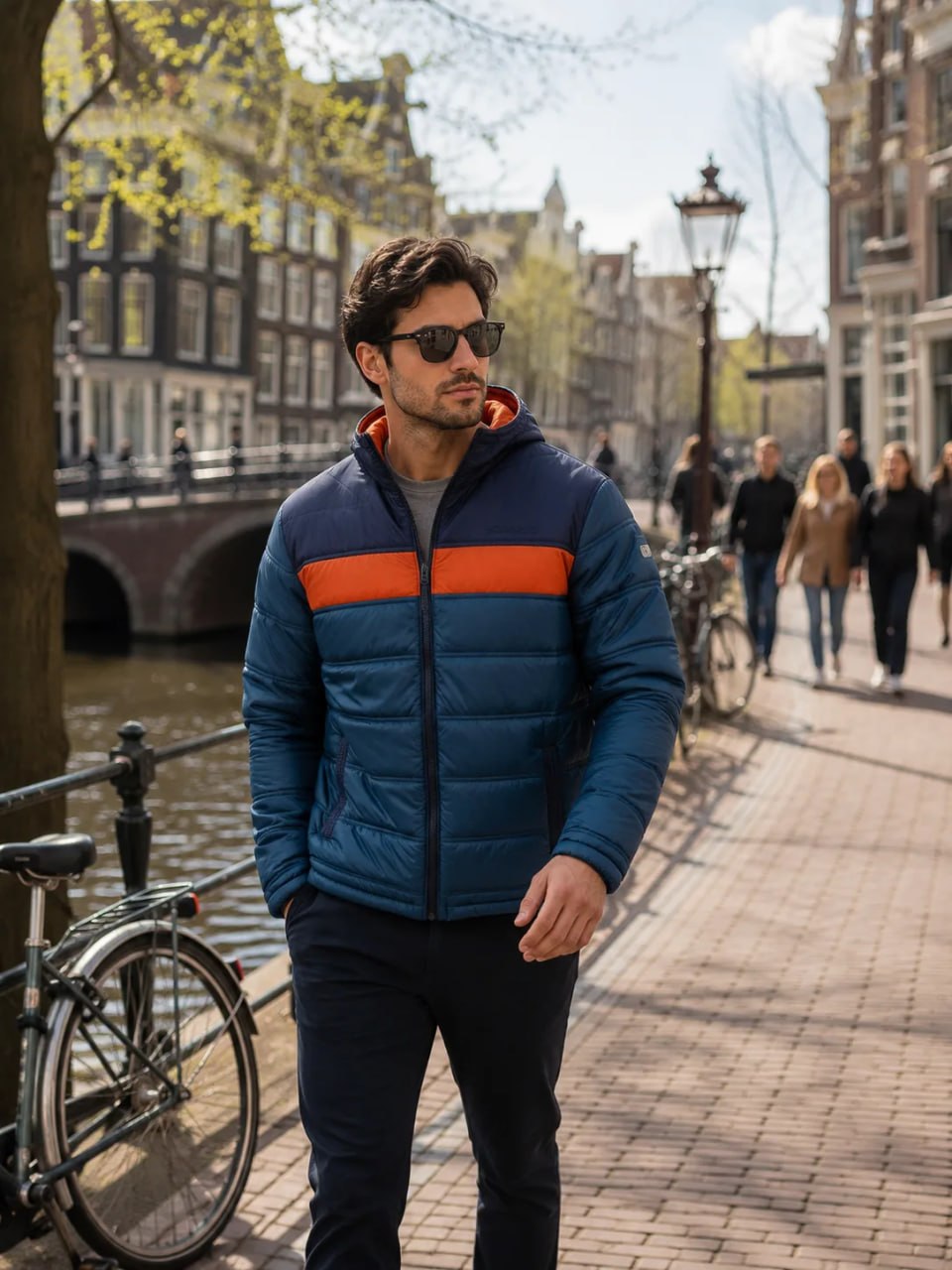 Man wearing a blue and orange jacket on a city street with buildings and bicycles in the background.
