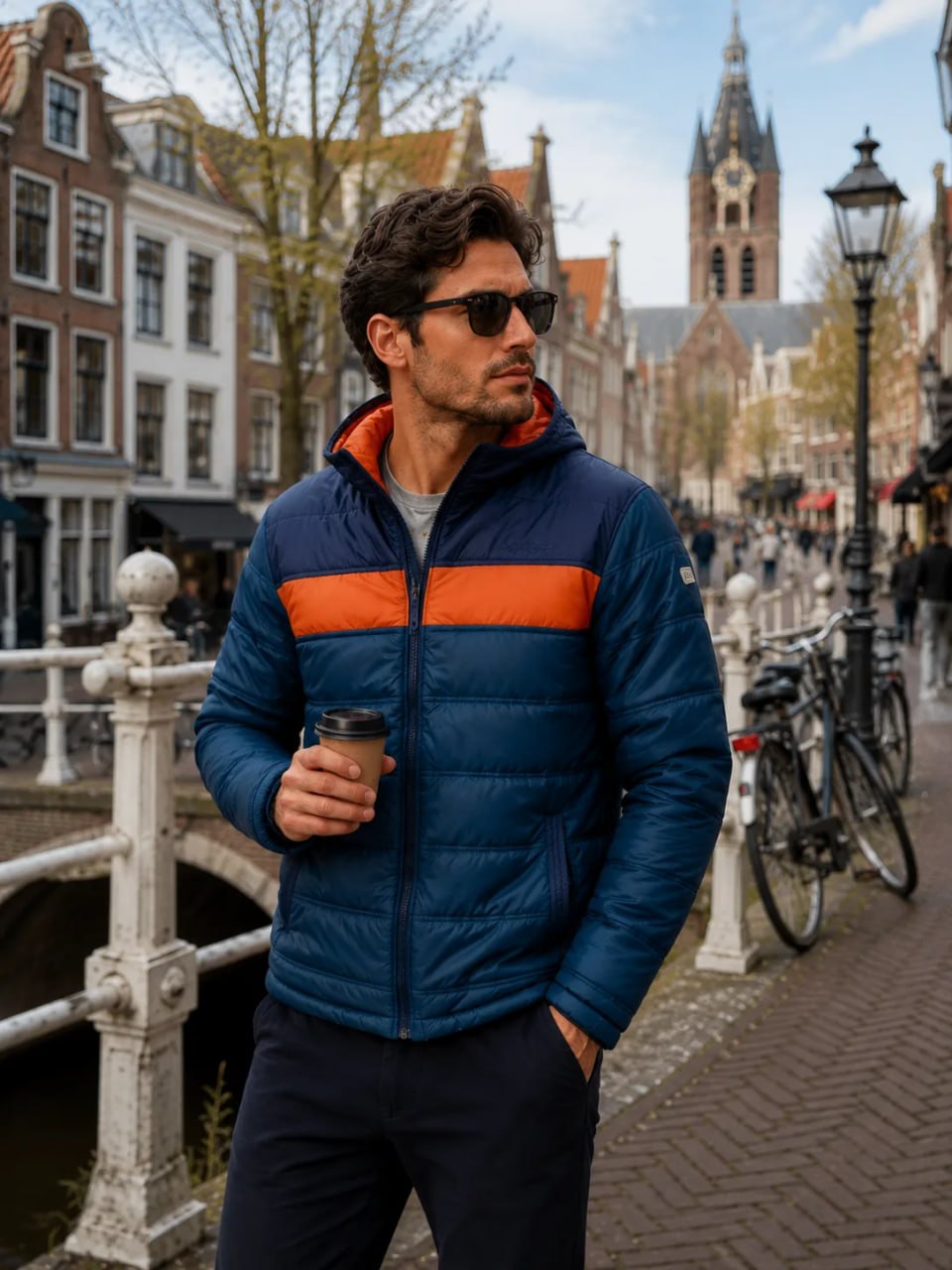 Man in a blue and orange jacket standing on a street in a European city.