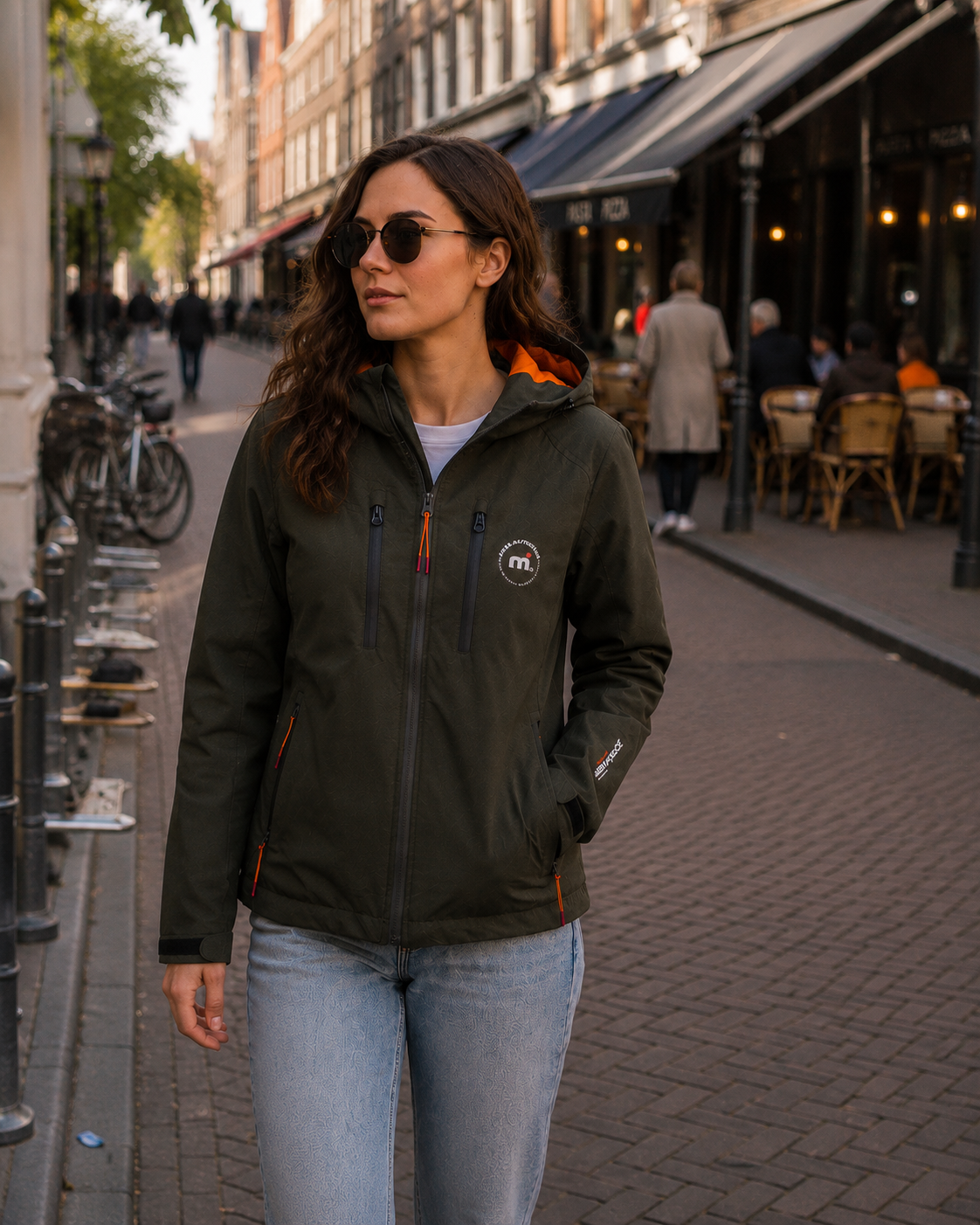 Woman wearing a black jacket with a logo on a city street