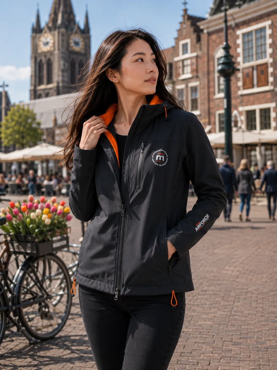 Woman wearing a black jacket with orange accents in an urban setting