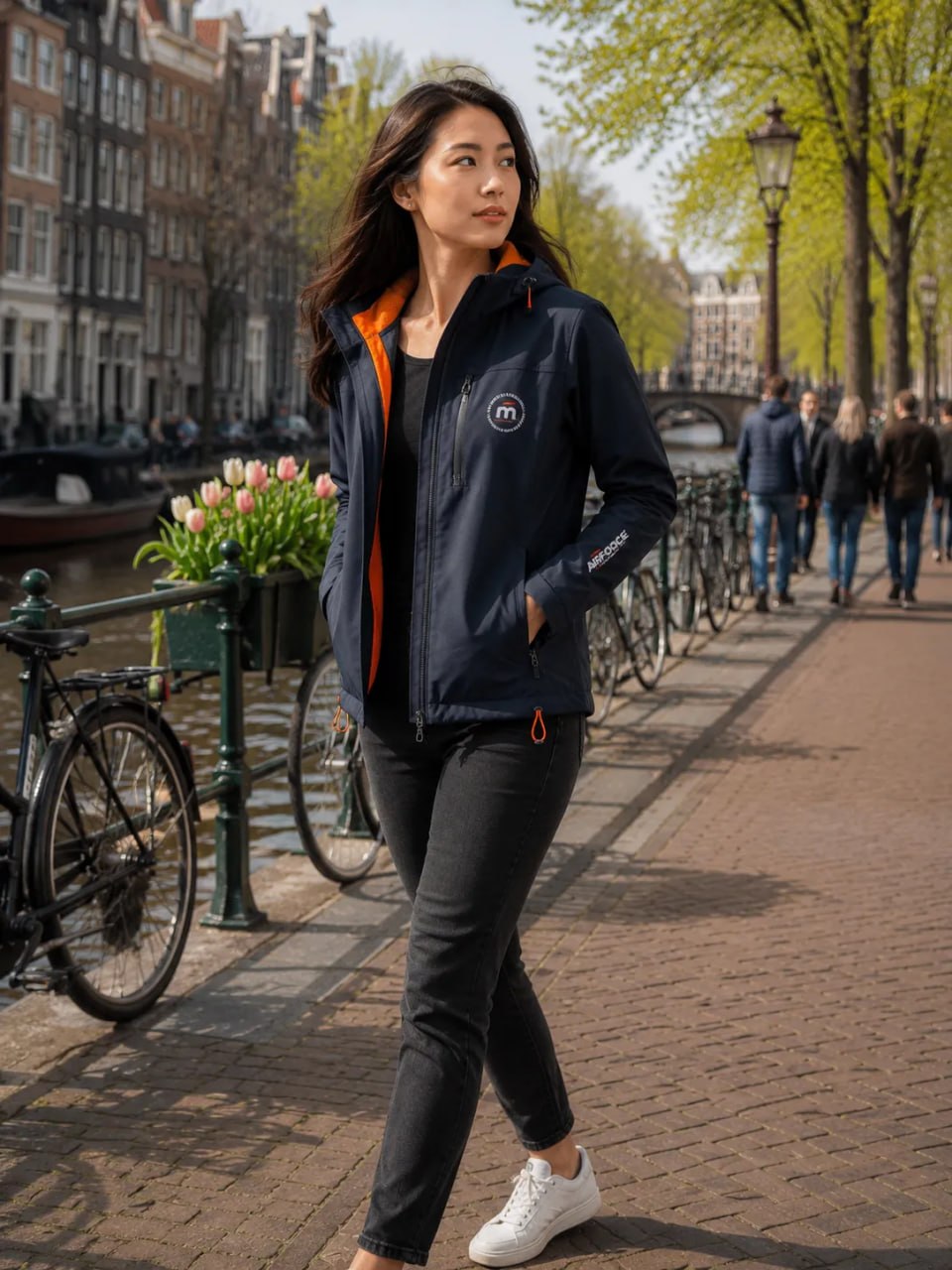 Woman in a blue jacket walking along a canal in a European city.
