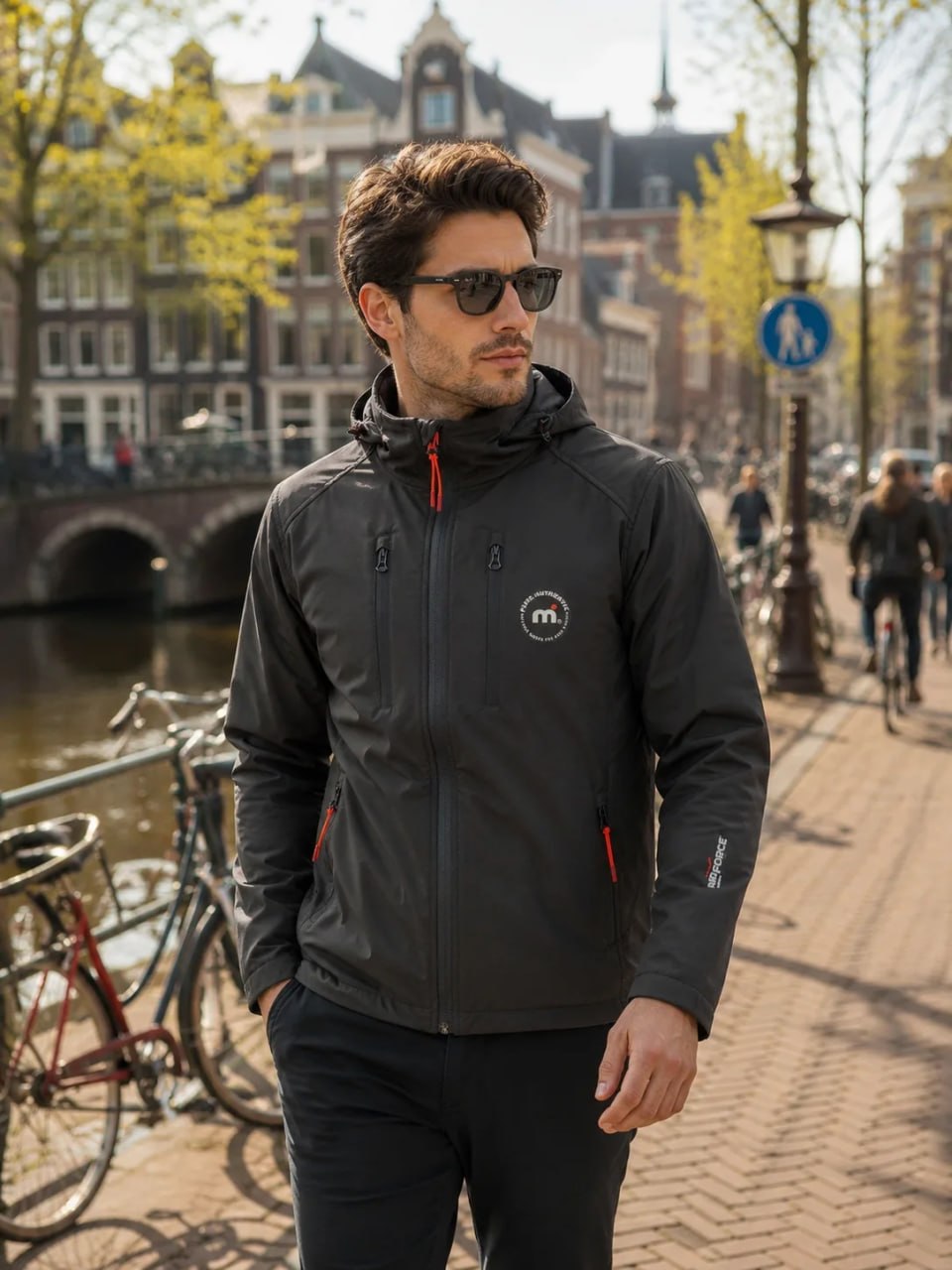Man wearing a black jacket with a brand logo on a city street.