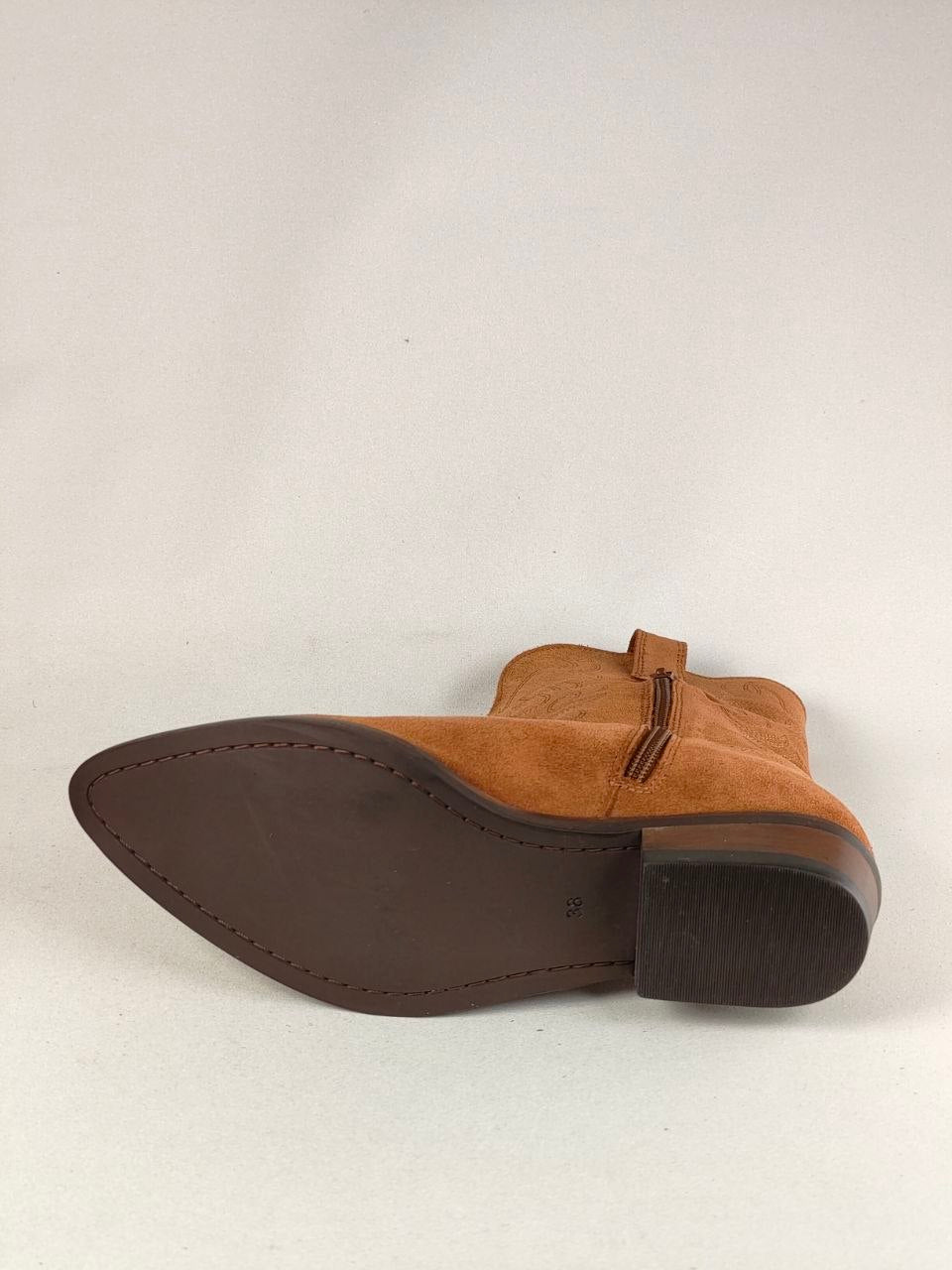 A single brown suede ankle boot shown from the side, displaying its dark brown sole, heel, and a matching pull tab near the collar, set against a plain light gray background.