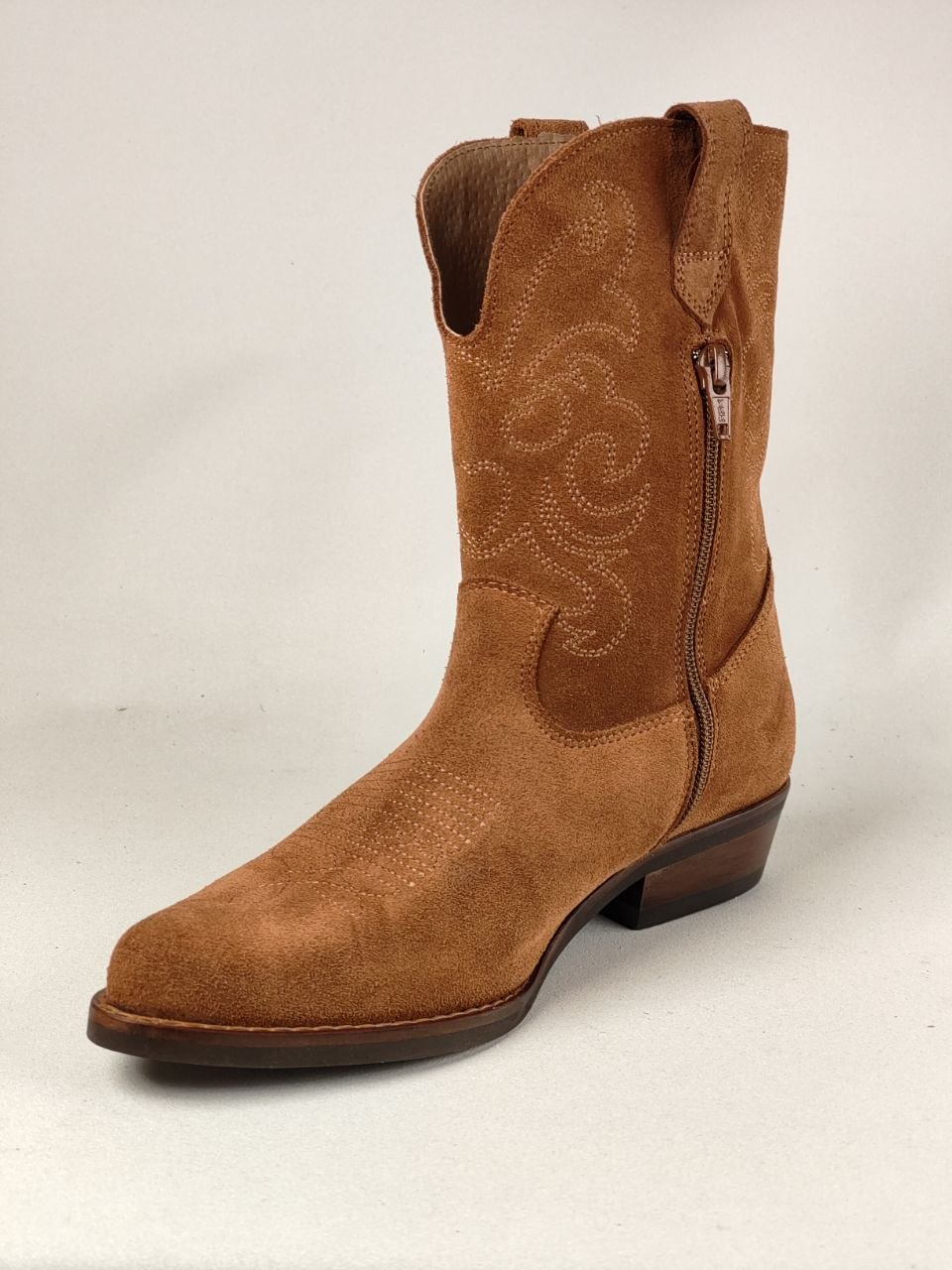 A single brown suede western boot with a side zipper, decorative stitched embroidery on the shaft, and a square toe, photographed against a light neutral background.