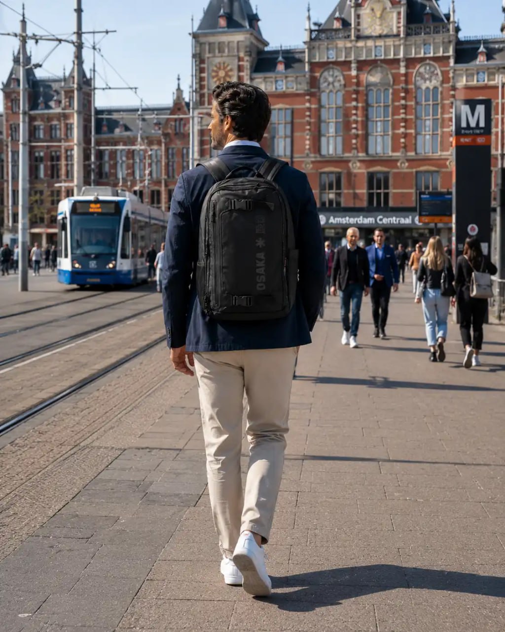 Man walking on a city street with a backpack, Amsterdam Central station in the background