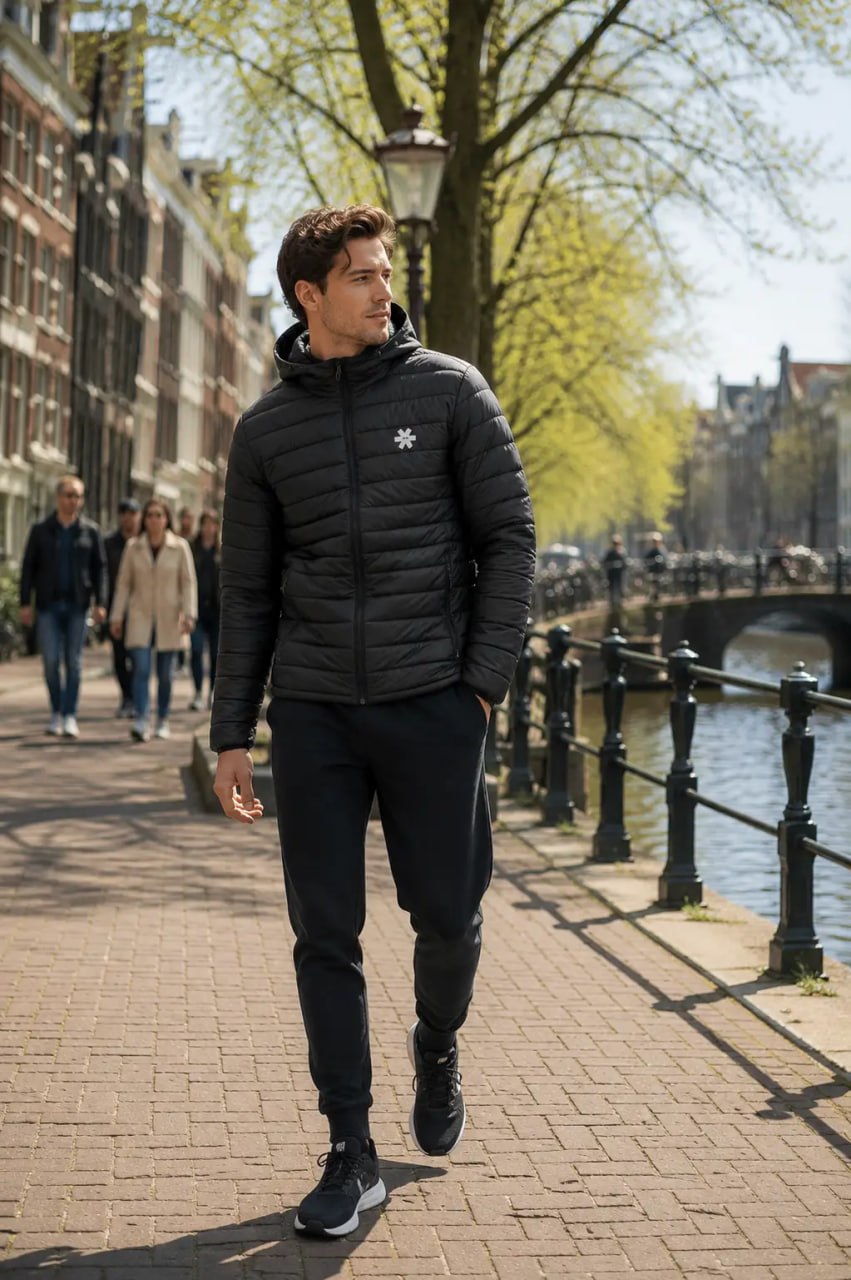 Man in a black puffer jacket walking along a canal in an urban setting