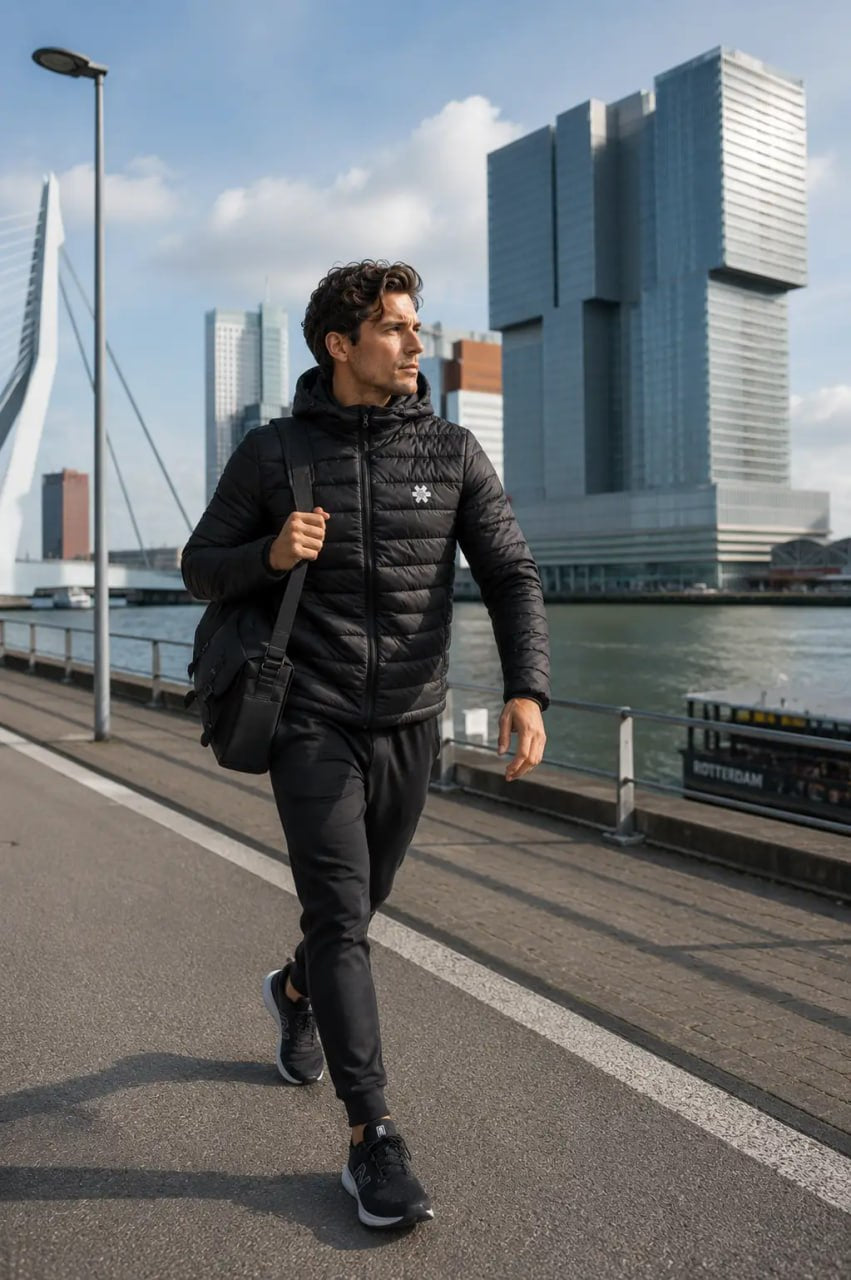 Man walking on a path by a waterfront with modern buildings in the background