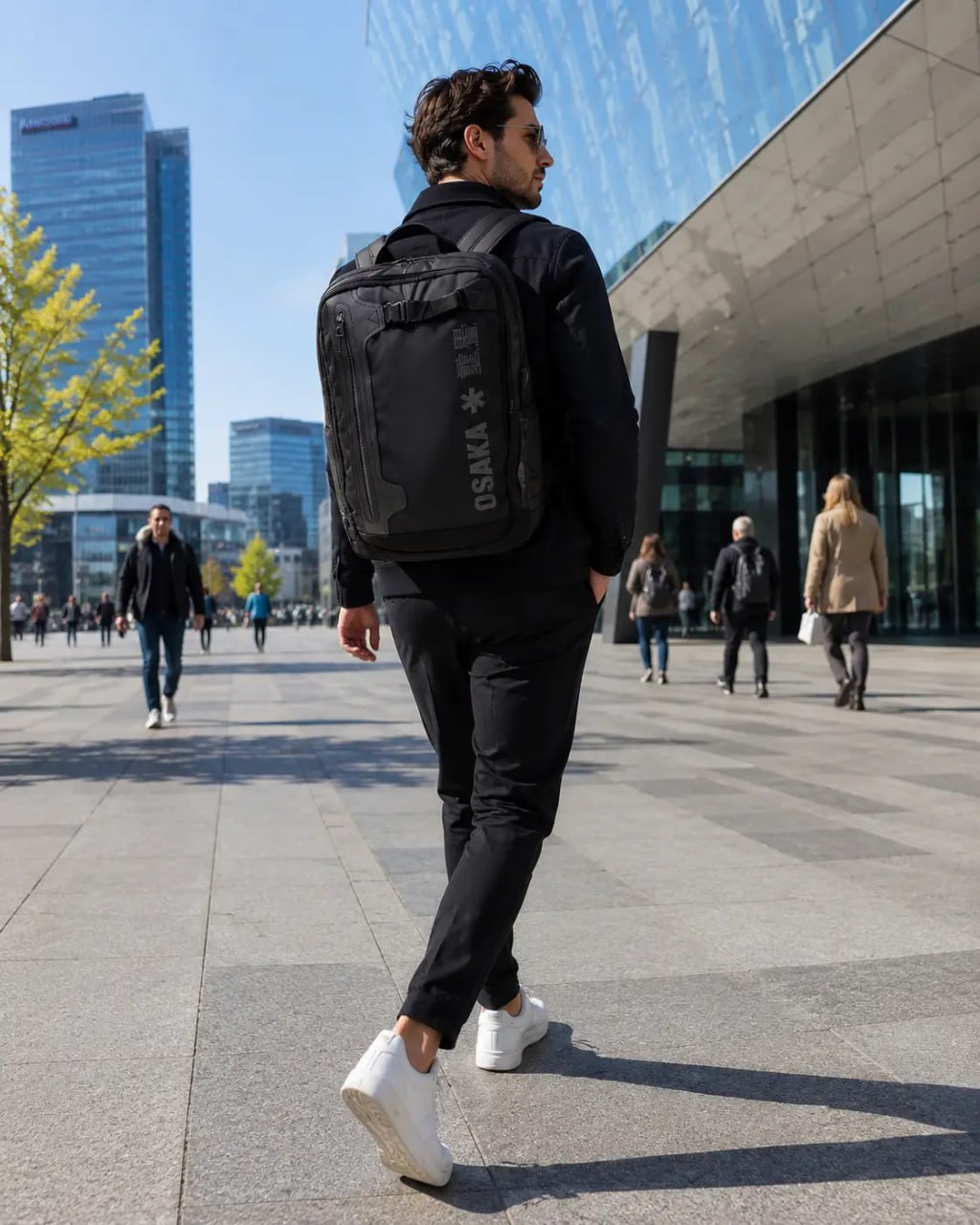 Man walking outdoors wearing a black backpack with 'USKA' branding.