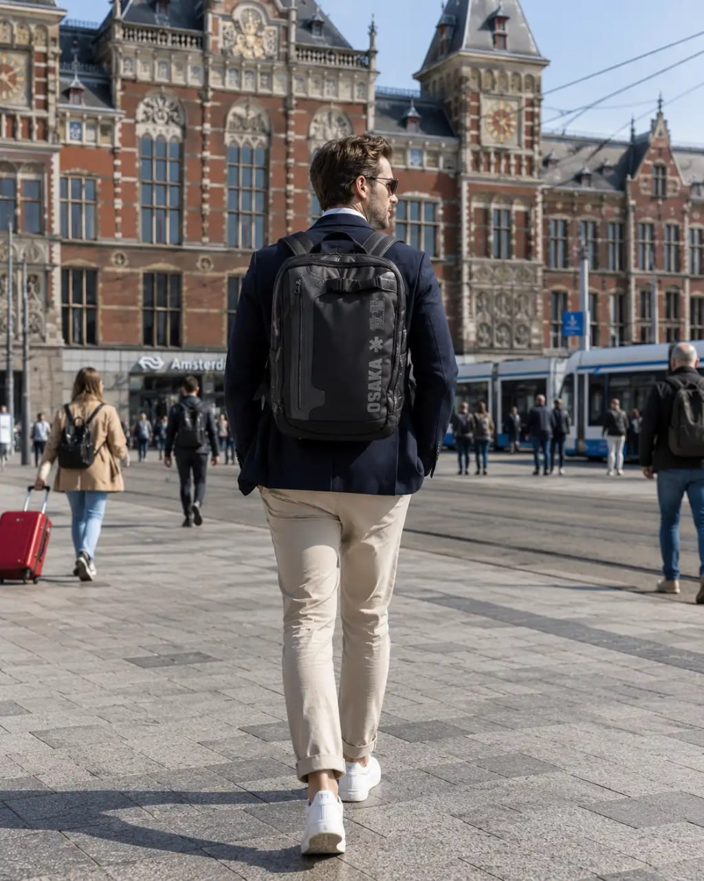 Man walking with a backpack in an urban setting with a large building in the background