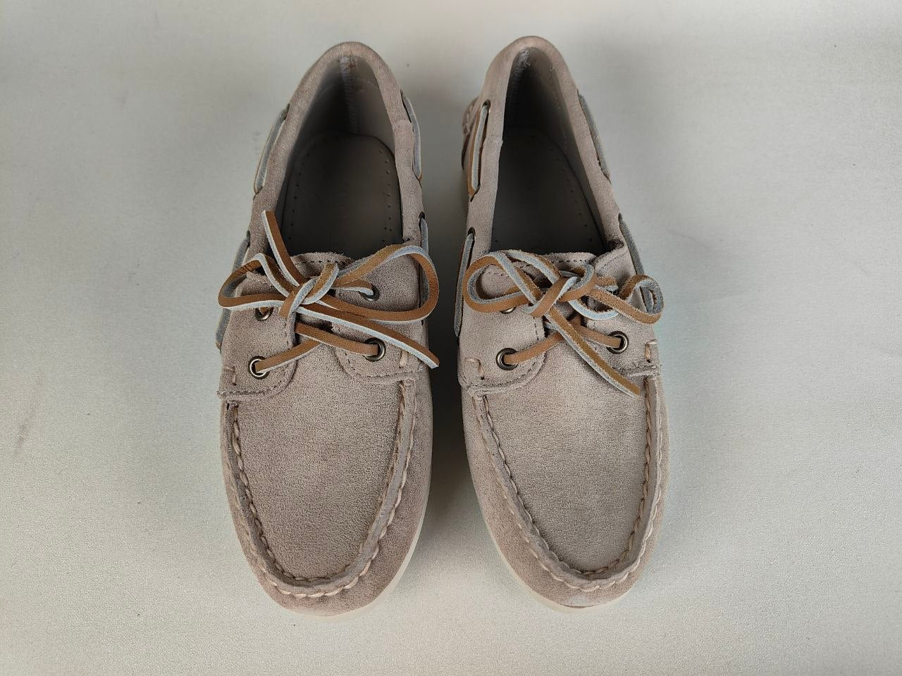 Pair of beige boat shoes on a light gray background