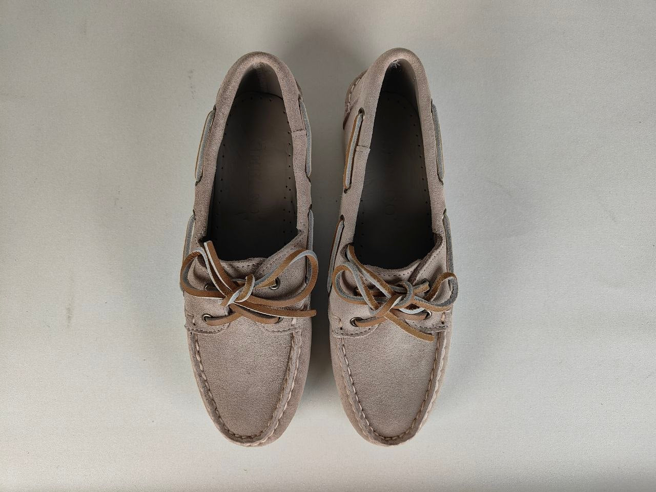 Pair of gray loafers with brown laces on a light gray background