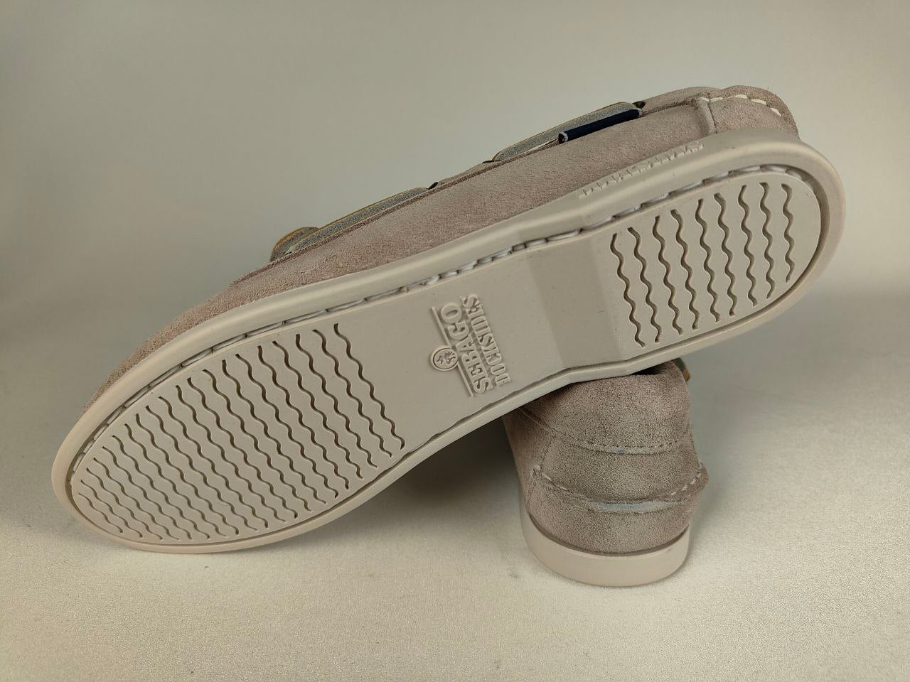 Close-up of a beige suede shoe sole with brand logo on a neutral background