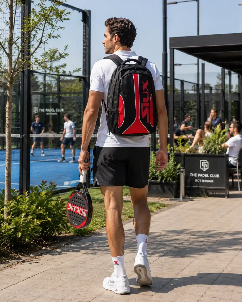 Man walking with a racket and a sports bag at The Padel Club.