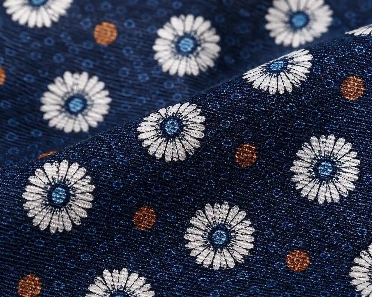 Close-up of a floral patterned fabric with white flowers and blue centers on a dark blue background.