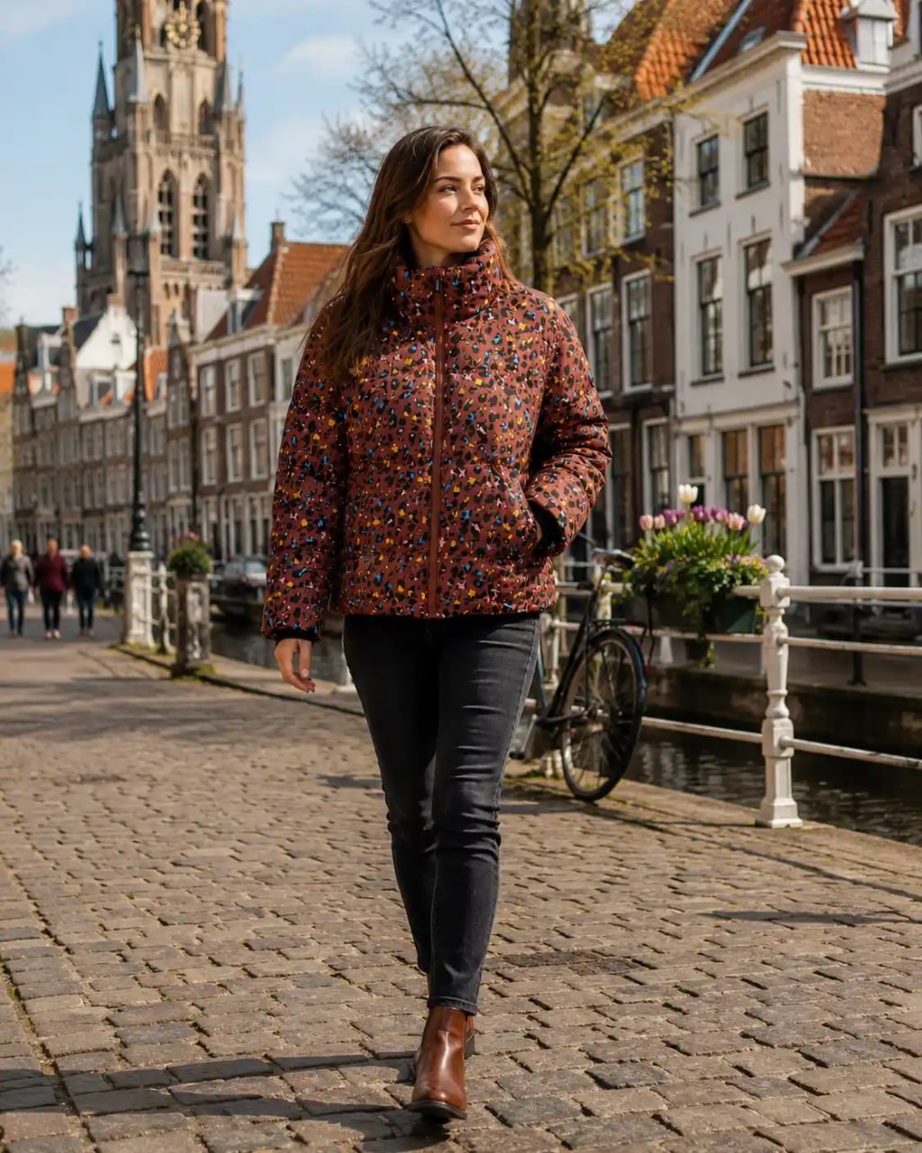 Woman with a colorful patterned Stronger heat short jacket on a cobblestone street in a European town with historic architecture.