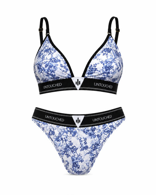 A two-piece bikini set with a blue and white floral toile pattern, featuring black trim and a black underband with the brand name 'UNTOUCHED' printed in white. The set includes a triangle bralette and a matching thong, displayed against a solid white background.